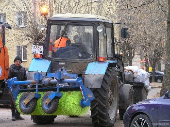 Трактор вывозит мешки с листвой.
